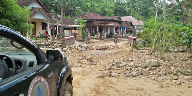 Material tanah longsor menutupi akses jalan desa.