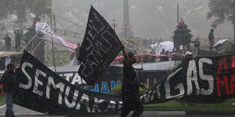 Aremanaia tetap menggelar aksi menuntut keadilan korban Tragedi Kanjuruhan meski diguyur hujan deras.