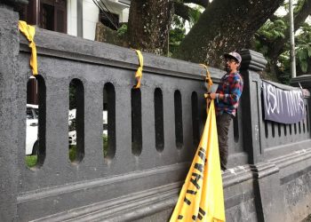 Totok Kacong, salah satu Aremania memasang kembali spanduk Usut Tuntas Tragedi Kanjuruhan yang diduga dicopot.