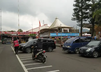 Salah seorang jukir resmi berompi di Alun-alun Kota Batu saat membantu parkir mobil pengunjung.