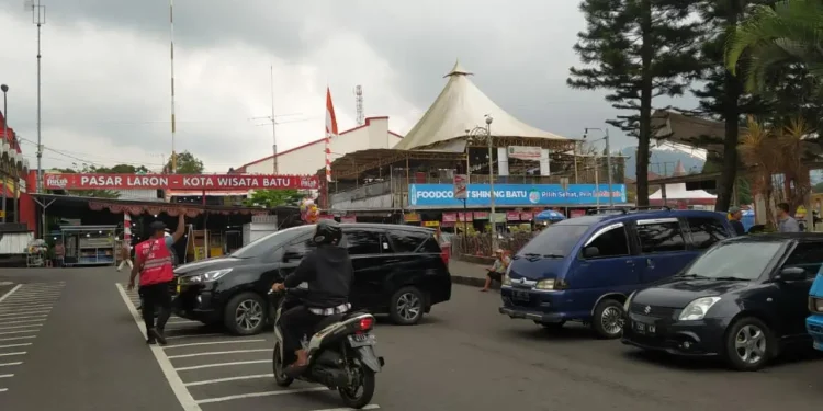Salah seorang jukir resmi berompi di Alun-alun Kota Batu saat membantu parkir mobil pengunjung.