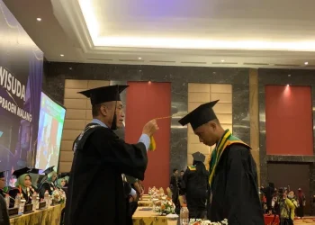Rektor ITSK RS dr Soepraoen saat mengukuhkn salah seeorang wisudawan.