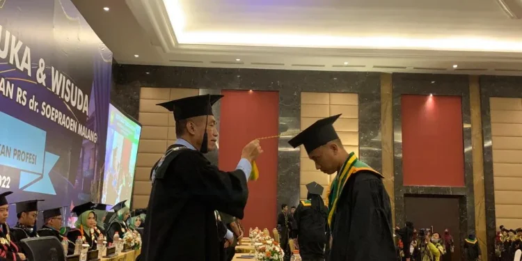 Rektor ITSK RS dr Soepraoen saat mengukuhkn salah seeorang wisudawan.