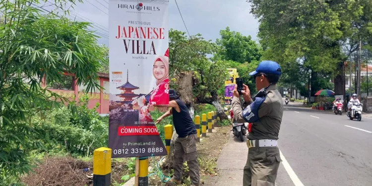 Petugas Satpol PP Kota Batu tengah menertibkan sejumlah reklame ilegal di jalan-jalan.