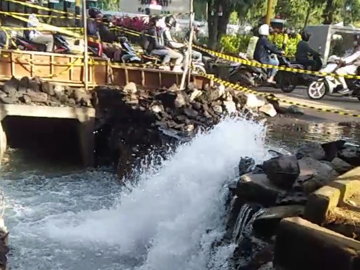 Semburan air dari pipa PDAM yang jebol akibat terkena axcavator pengerjaan drainase di Jalan Veteran, Kota Malang. 