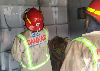 Petugas melakukan pembasahan agar api benar-benar padam.