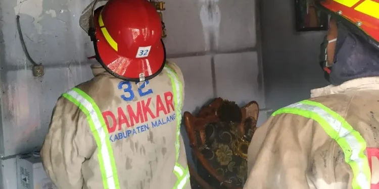 Petugas melakukan pembasahan agar api benar-benar padam.