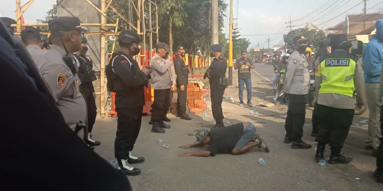 Seorang Aremania bersujud dan menangis histeris di hadapan anggota Brimob sembari meluapkan duka karena ditinggal anak.