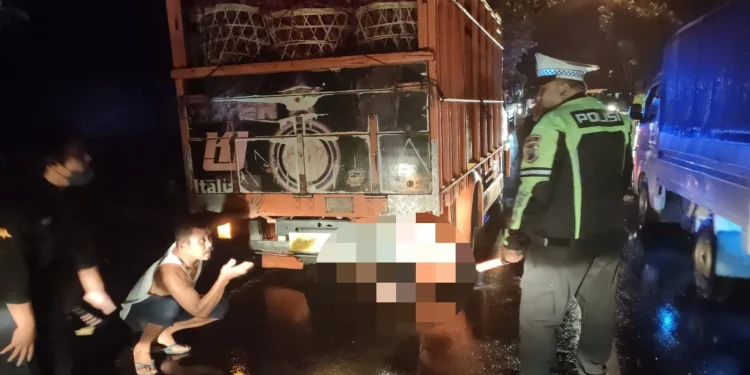 Petugas dan warga mengevakuasi korban yang terjepit di kolong truk.