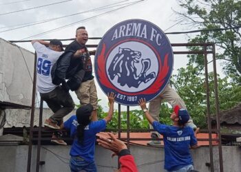 Aremania melakukan pemasangan kembali Logo Arema di Kandang Singa.