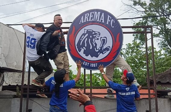Aremania melakukan pemasangan kembali Logo Arema di Kandang Singa.