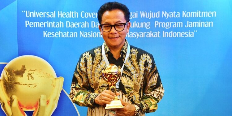 Drs. H. Sutiaji, Wali Kota Malang menunjukkan piala penghargaan UHC dari Kemenko PMK RI.