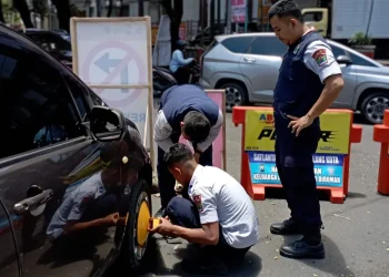 Petugas Menggembok mobil yang parkir liar di tepi jalan.