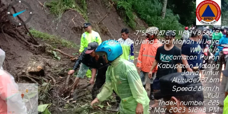 Petugas dan masyarakat melakukan pembersihan material tanah longsor.
