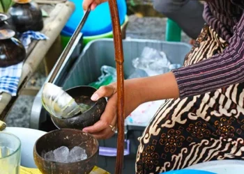 Seorang penjual dawet yang tengah menyajikan minuman es dawet (Foto/Canva)