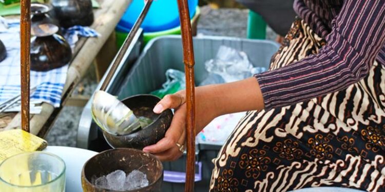 Seorang penjual dawet yang tengah menyajikan minuman es dawet (Foto/Canva)