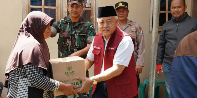 Sanusi menyerahkan bantuan kepada warga yang kurang mampu.