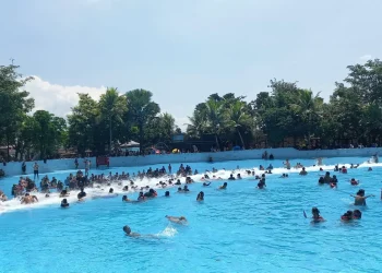 Pengunjung menikmati terjangan ombak buatan di wahana Tsunami.