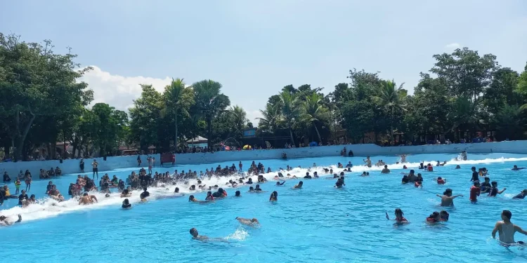 Pengunjung menikmati terjangan ombak buatan di wahana Tsunami.