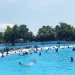 Pengunjung menikmati terjangan ombak buatan di wahana Tsunami.