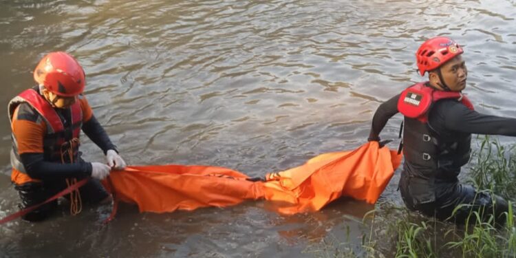 Petugas melakukan evakuasi jenazah bocah yang terseret aliran Sungai Brantas di Kota Malang.