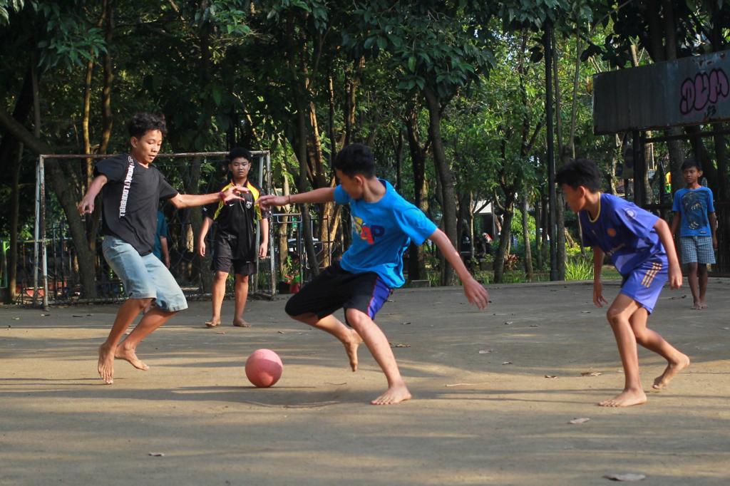 Beberapa anak bermain sepak bola di Taman Merbabu, Kota Malang, Senin (10/7/2023).