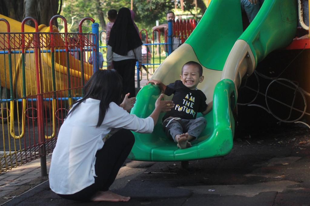 Seorang anak bermain playground di Alun-Alun Merdeka, Kota Malang, Senin (10/7/2023).