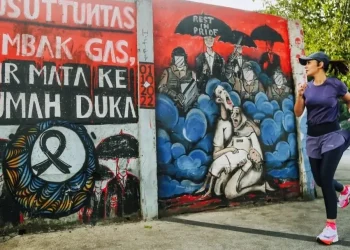 Unggahan Najwa Shibab berfoto dengan mural yang berisi pesan tuntutan usut tuntas Tragedi Kanjuruhan.