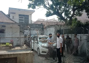 Petugas berjaga di balik pagar saat Ditreskrimsus Polda Jatim melakukan penggeledahan di rumah tua Jalan Halmahera Kota Malang.