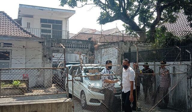 Petugas berjaga di balik pagar saat Ditreskrimsus Polda Jatim melakukan penggeledahan di rumah tua Jalan Halmahera Kota Malang.
