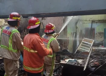Petugas melakukan pemadaman di tempat cuci motor yang terbakar.