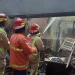 Petugas melakukan pemadaman di tempat cuci motor yang terbakar.
