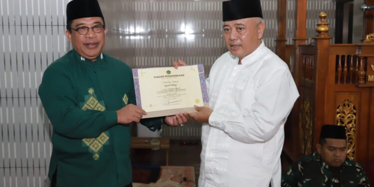 Kepala Kantor Kementerian Agama Kabupaten Malang, Sahid (kiri) menyerahkan penghargaan kepada Bupati Malang, Sanusi (kanan).