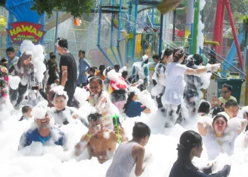 Pengunjung asyik bermain busa setelah ombak tsunami di Hawai Waterpark, Minggu (17/9/2023.
