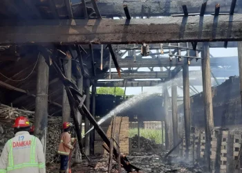Petugas melakukan pemadaman di tempat pembuatan batu bakar yang terbakar.