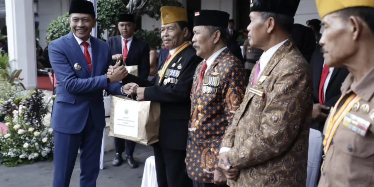 Pj Wali Kota Malang, Wahyu Hidayat, memberikan penghargaan pada orang-orang yang berjasa.
