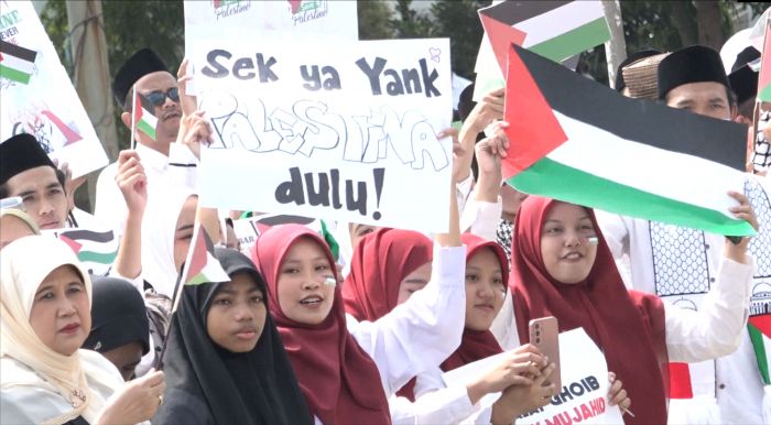 Para peserta aksi solidaritas untuk Palestina membentangkan poster.