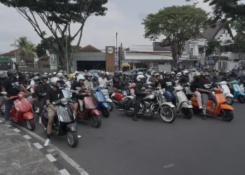 Puluhan pengendara Vespa mengelilingi jalanan di Kota Malang.