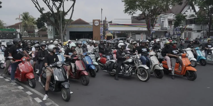 Puluhan pengendara Vespa mengelilingi jalanan di Kota Malang.