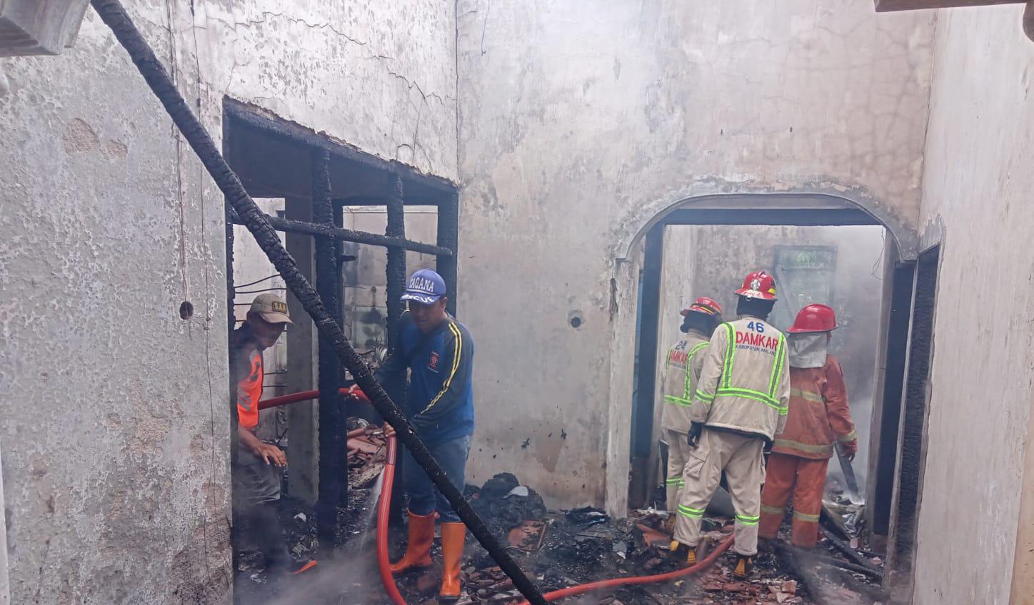 Petugas melakukan pemadaman pada kebakaran rumah di Kepanjen milik Winarmi yang terbakar. 