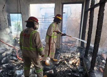Petugas melakukan pemadaman pada kebakaran rumah di Kepanjen milik Winarmi yang terbakar.