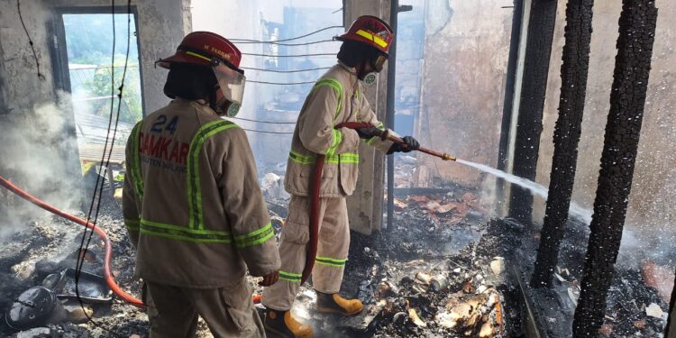 Petugas melakukan pemadaman pada kebakaran rumah di Kepanjen milik Winarmi yang terbakar.