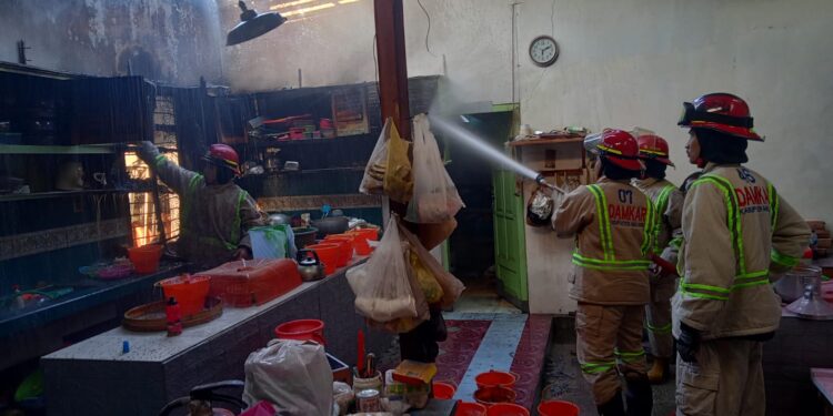 Petugas melakukan penanggulangan kebakaran di sebuah rumah di Bululawang.