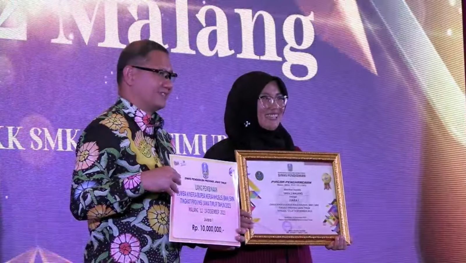 Kepala Dinas Pendidikan Jawa Timur Aries Agung Paewai bersama Waka Humas SMKN 2 Malang Eviatun Khaeriah dalam penyerahan piagam penghargaan.