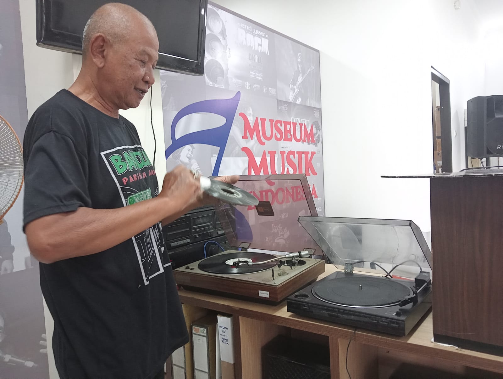 Usman memutar piringan hitam rekues pengunjung museum. Foto/Fitrothul M.