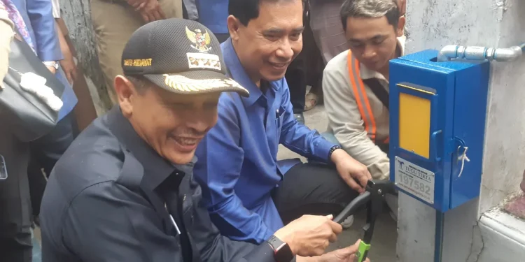 Pj Wali Kota Malang, Wahyu Hidayat meresmikan dan mengoperasikan sambungan atau meteran baru untuk warga di Jalan Muharto, Kota Malang. (Foto/M Sholeh)