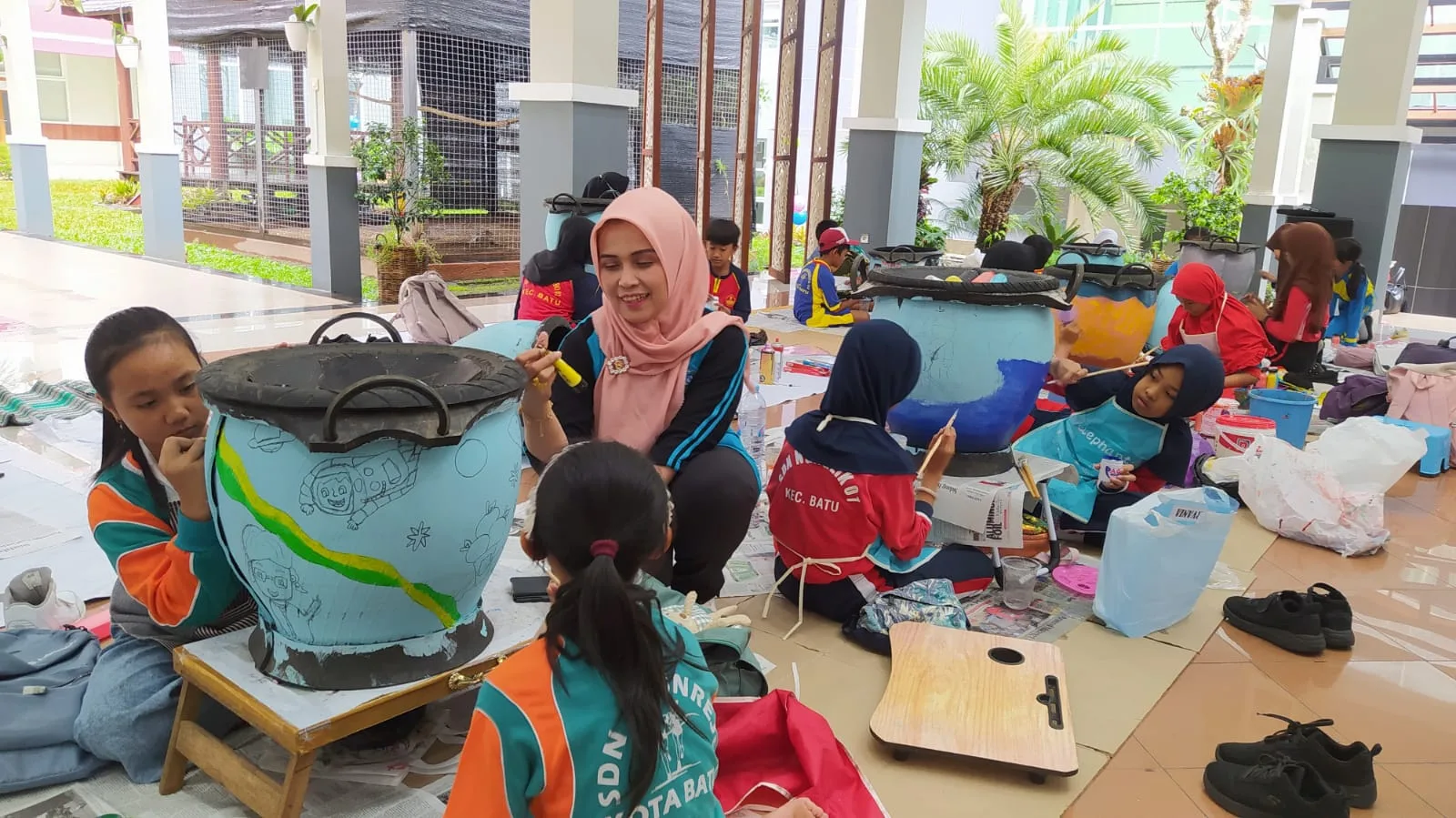 Pj Ketua TP PKK Kota Batu Dwi Mardiana Susilawati saat berinteraksi dengan anak-anak penyandang autis yang asyik melukis tong sampah. Foto: Azmy