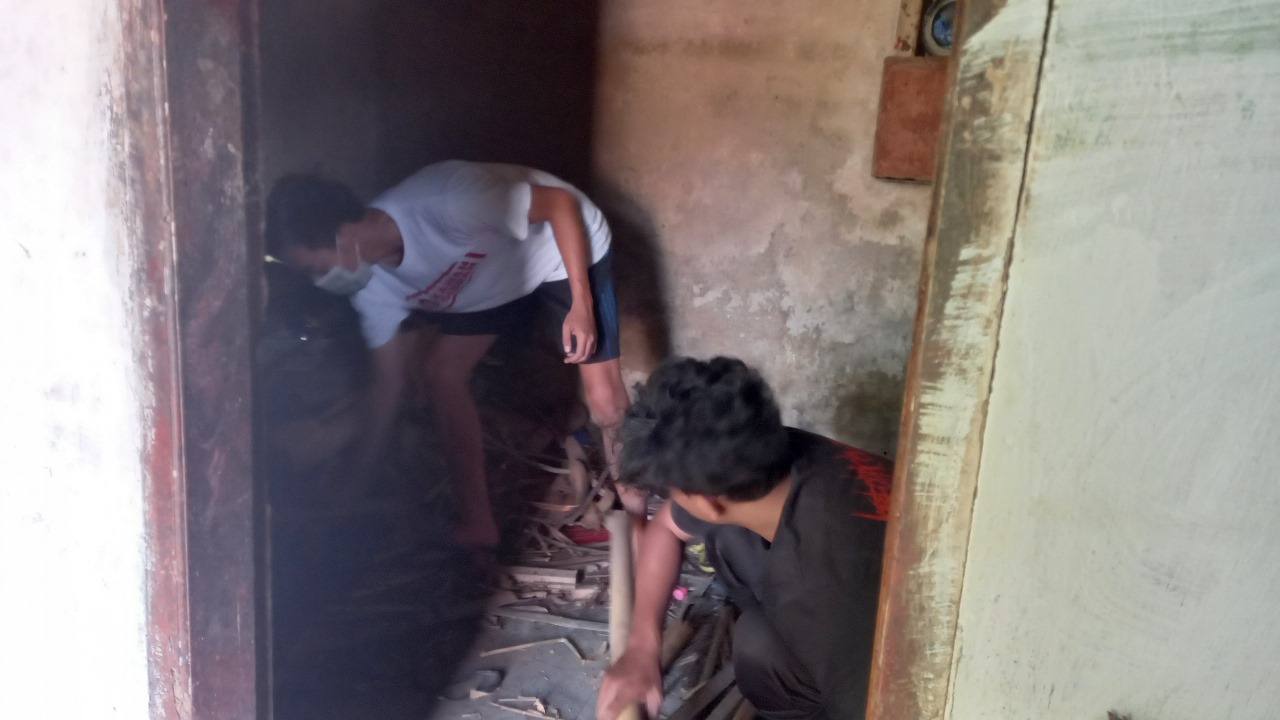 Mahasiswa Vokasi UMM membersihkan kamar belakang yang berisi kayu bakar dan daun kelapa kering. Foto: Aisyah Nawangsari Putri