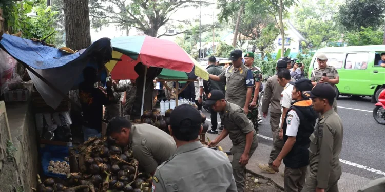 Petugas Satpol PP saat penertiban membongkar lapak liar para pedagang di pinggir jalan. Foto: Azmy