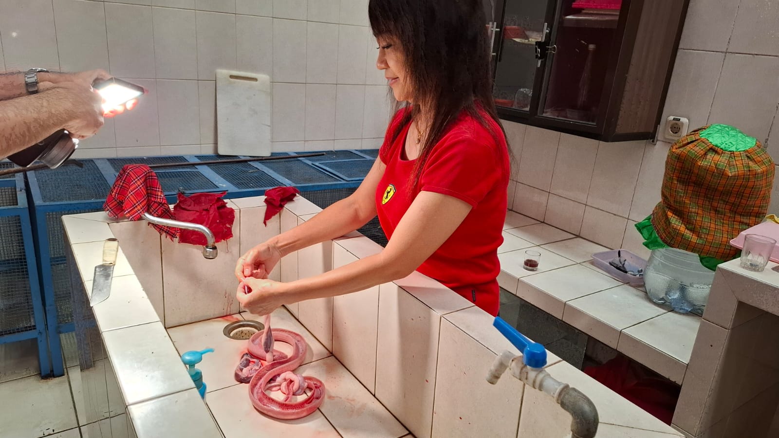 Titik membersihkan ular kobra yang baru disembelih. Foto: Aisyah Nawangsari Putri